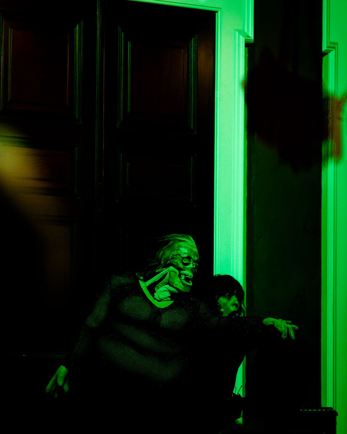A puppet figure appears in green light in a doorway.