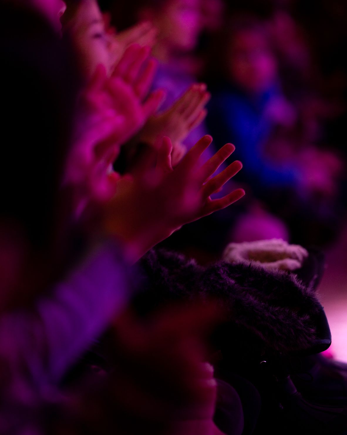 Children’s hands clapping in pink light.