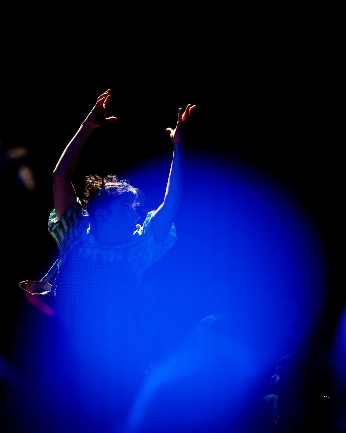 A figure with raised arms floats above a glowing blue sphere in the dark.