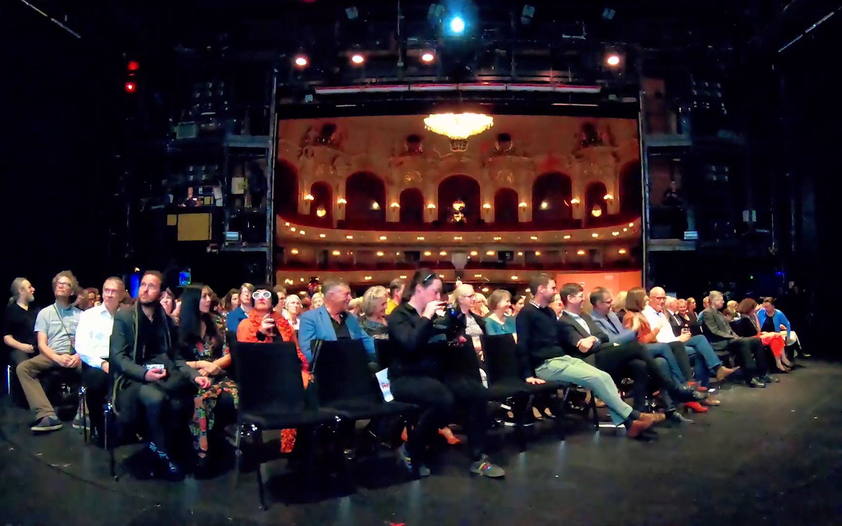 The audience seated on the stage, looking out into the auditorium.