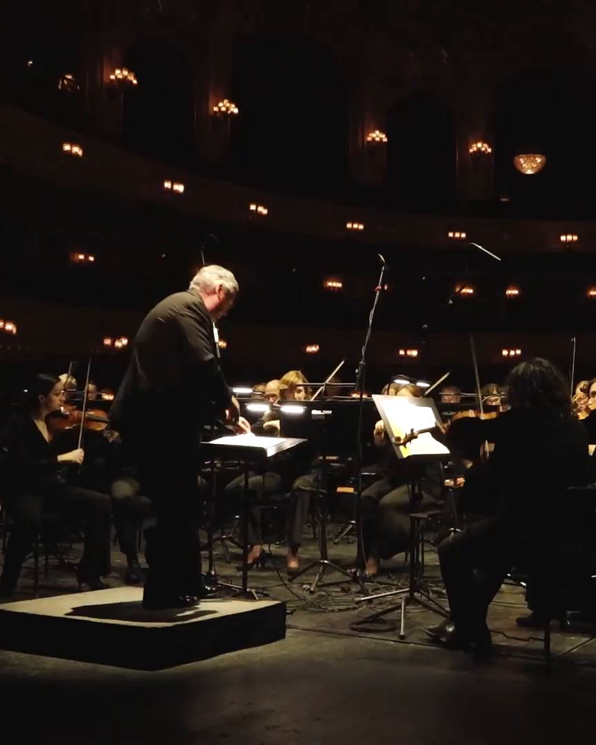The conductor in front of the orchestra on the stage.
