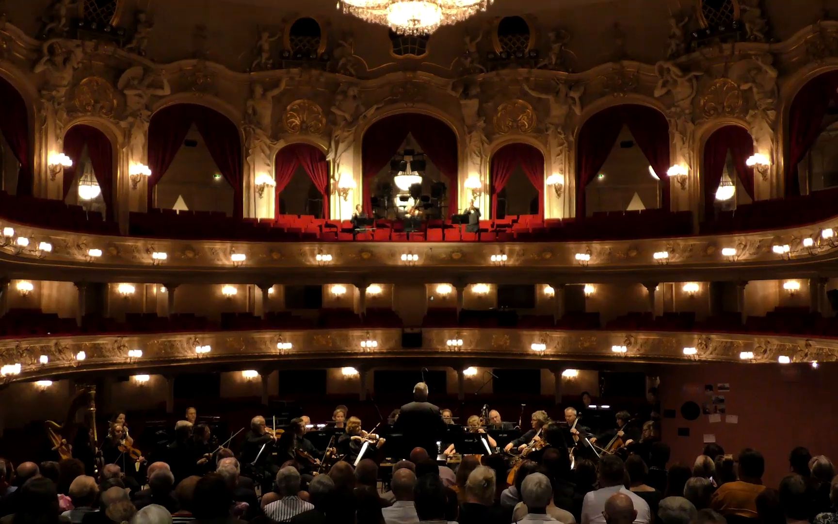 The gilded tiers of the Komische Oper, the orchestra in front of the audience.