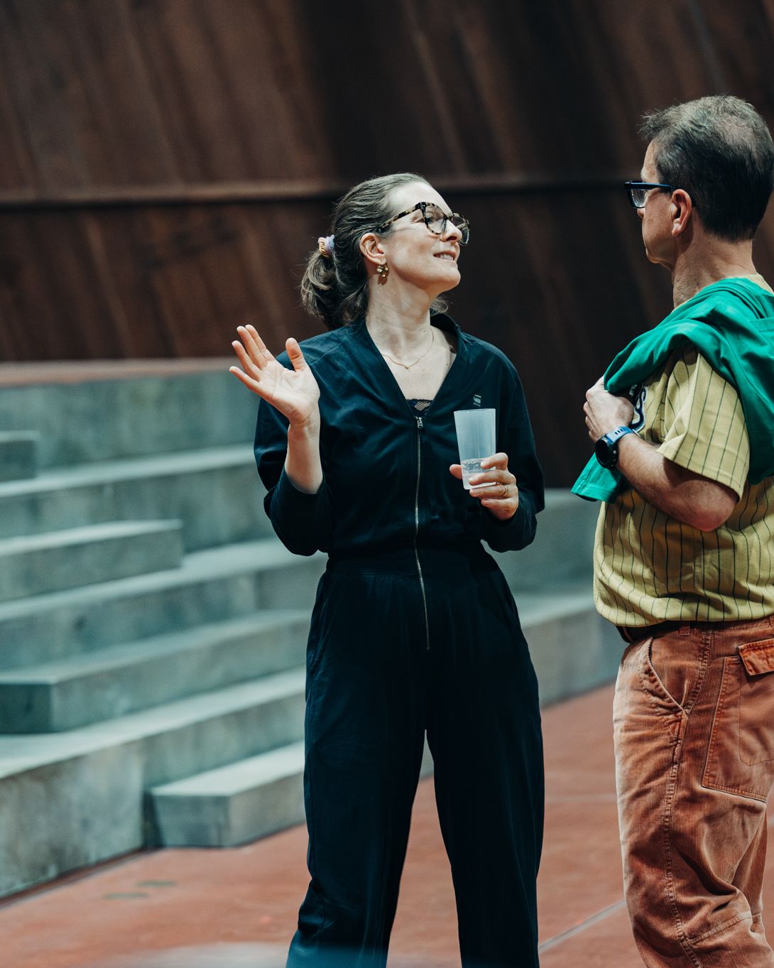 Two people talk on the steps of the rehearsal hall.