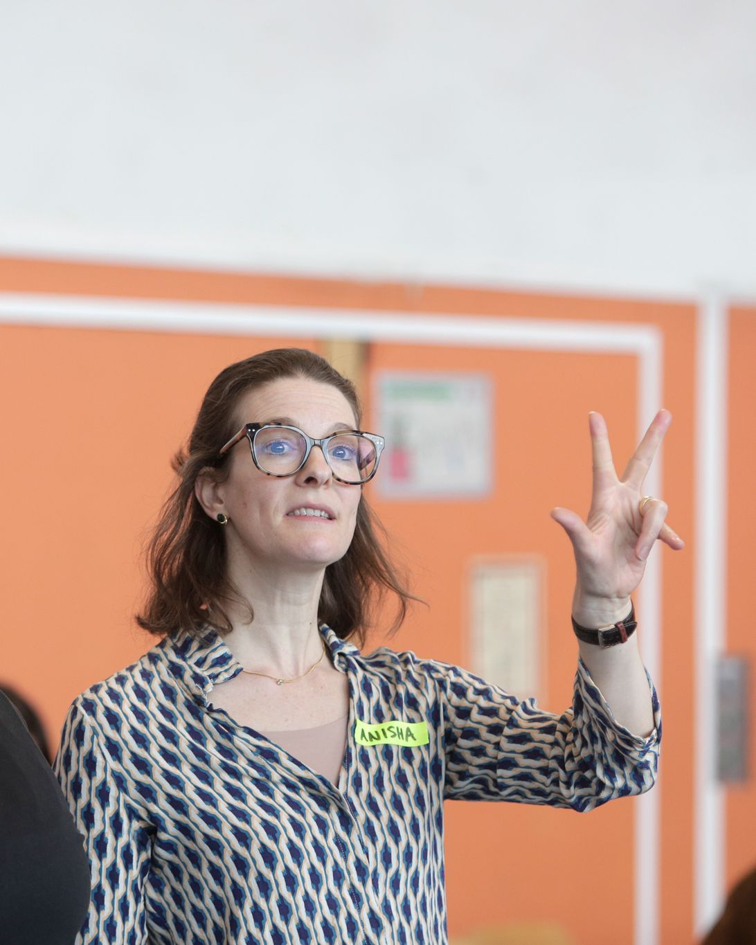 A woman explains a scene with a raised hand.