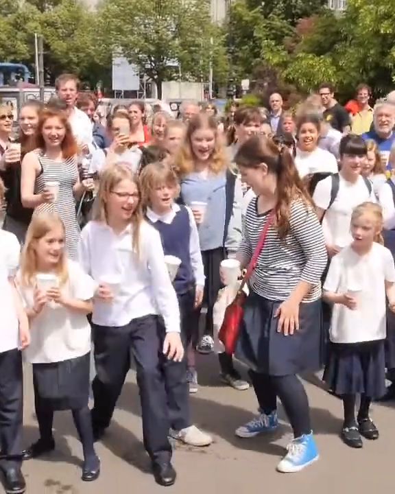 Schoolchildren with paper cups see the bus off.